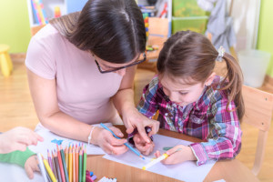 Kindergarten Teacher Supporting Child in Creative Activities